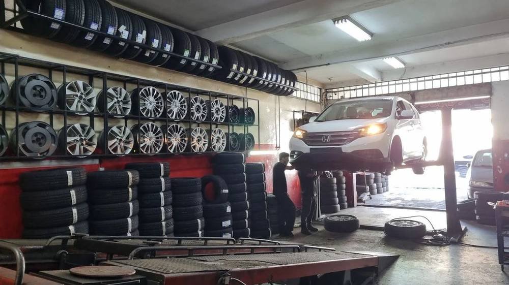Carro sobre o elevador da Slink, com estoque de rodas e pneus na parede ao fundo
